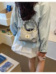 Detail view of a grey pleated handbag with lace trim and cute bear patch design