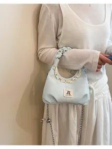 Close-up of light blue pleated handbag featuring cute bear patch and elegant lace trim.