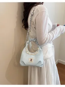 Cute light blue pleated handbag with white lace trim and bear patch detail shown on model