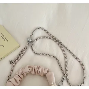 Close-up of a pink pleated handbag with silver chain strap and adjustable metallic ball