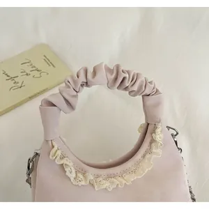 Close-up of pink handbag with pleated scrunchie handle and delicate lace trim.