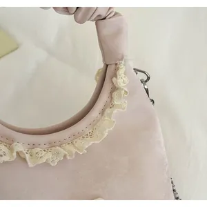 Close-up detail of a minimalist pink handbag featuring delicate lace trim and a trendy scrunchie handle
