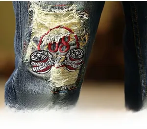 Detailed view of vintage ripped denim jeans featuring colorful embroidery and patches