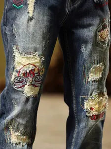 Close-up detail of vintage distressed denim jeans with heavy patchwork and embroidery