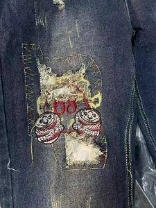 Close-up of vintage distressed denim jeans featuring an embroidered patch with red 68 detail