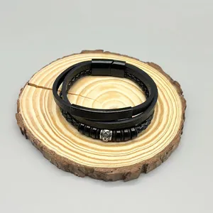 Detail view of men's vintage multi-layer black leather braided bracelet on wood base