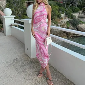 Summer women's halter maxi dress with pink marble swirl print in a coastal setting