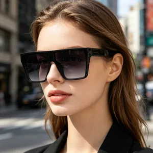 Woman wearing oversized square black sunglasses in a sunny urban street setting