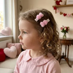 Nahaufnahme eines Mädchens mit zwei rosa Plüsch-Haarspangen in Herzform im Haus