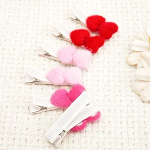 Detailaufnahme von Plüsch-Haarspangen mit Herzen in Rot und Rosa für kleine Mädchen.