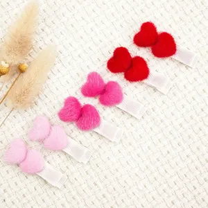 Set mit sechs herzförmigen Haarspangen aus rosa und rotem Plüsch für kleine Mädchen.