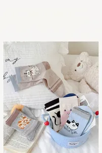 Variety of cute cartoon cat patterned cotton mid-tube socks displayed in a blue basket
