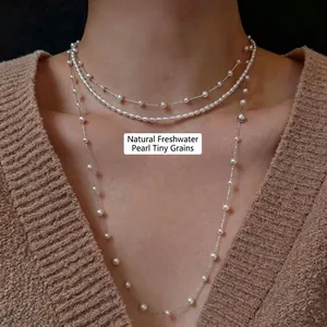 Détail d'un collier de perles d'eau douce à trois couches sur un pull en maille beige