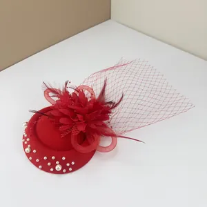 Close-up of red vintage fascinator hat with feathers, mesh veil and pearl accents