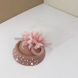 Elegant vintage pink fascinator hat with silk flower, mesh veil, and pearl accents