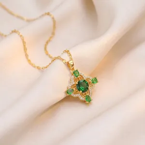 Collier doré élégant avec pendentif fleur en zircon vert émeraude sur fond de soie.