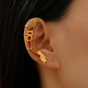 Detailed view of minimalist gold cat and dog silhouette ear cuff on ear