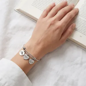 Close-up view of a stainless steel heart charm bangle with MOM and Love engravings