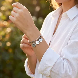 Lifestyle view of an adjustable stainless steel heart charm bracelet with MOM engraving