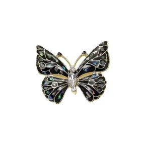 Macro detail of elegant black enamel butterfly brooch with iridescent shell and rhinestones