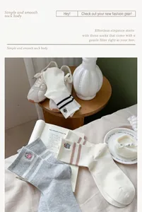 Detail view showing three pairs of striped socks with cute bear embroidery on soft white bedding
