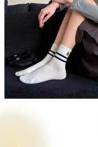 Close-up of white mid-tube socks with black stripes and a small bear embroidery detail