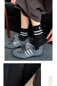 Close-up view of black mid-tube socks with cute bear embroidery and white stripes