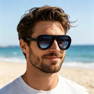 Gros plan d'un homme portant des lunettes de soleil aviateur noires sur la plage.