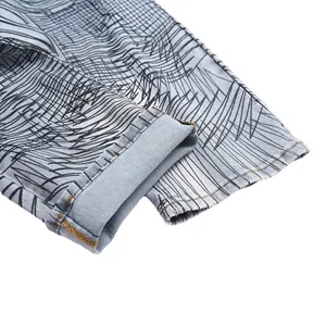 Men's flared jeans detail featuring black abstract line print on light blue denim fabric.