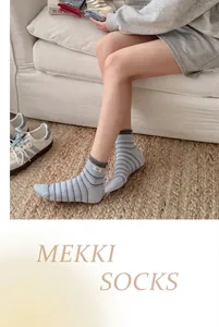 Casual colorful striped combed cotton mid-calf socks worn by a model on a sofa