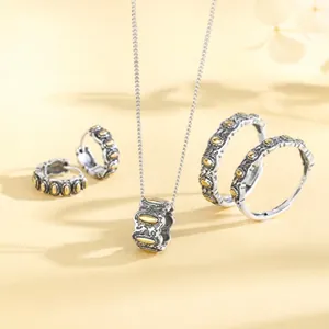 Close-up view of a textured silver jewelry set featuring elegant golden accents and fine details.