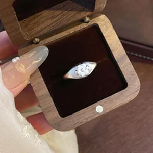 Close-up detail of a minimalist s925 silver kitten ring inside a wooden jewelry box