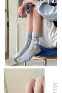 Detailed view of cute cartoon dog embroidery on grey combed cotton mid-calf socks.