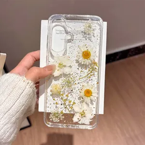 Macro detail of a clear Samsung case with real daisy flowers and gold foil accents.