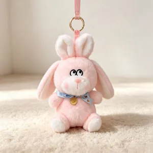 Cute pink plush rabbit keychain with blue bowtie and golden pendant detail