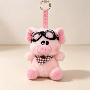 Detail of a cute pink pig plush keychain with retro goggles and a checkered bowtie