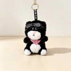 Close-up of a cute plush cat keychain with black goggles and a red gingham scarf.