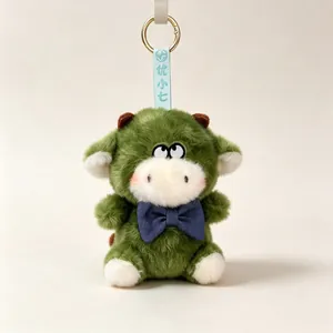 Detailed view of a green plush animal keychain with a blue bow tie and gold ring.