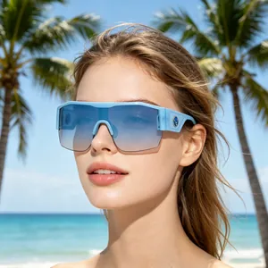 Close-up of blue Y2K oversized cycling sunglasses with gradient lenses on beach