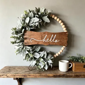 Artificial greenery wreath with wooden beads and a white cursive 'hello' wooden sign