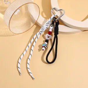 Detailansicht eines stylischen Herz-Schlüsselanhängers mit schwarz-weißen Flechtquasten.