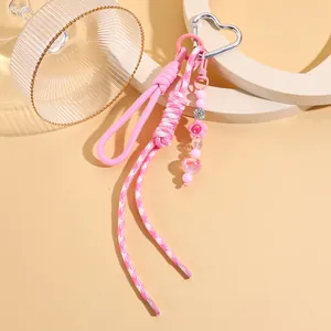 Detail eines rosa geflochtenen Herz-Schlüsselanhängers mit Perlen und Silberverschluss.