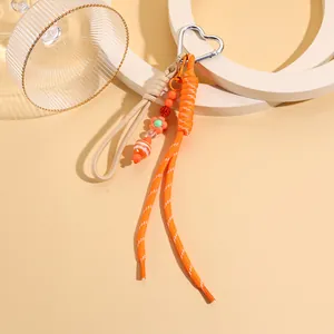 Detail eines süßen orangefarbenen Taschenanhängers mit Herzclip und Perlen