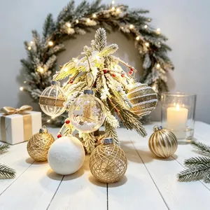 Festive set of transparent and golden Christmas ball ornaments on a small snowy tree