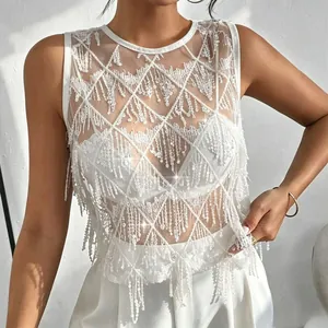 Détail du haut en maille à paillettes blanches avec franges élégantes et losanges.