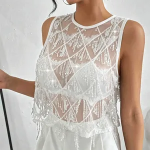 Détail d'un haut de fête en maille blanche avec paillettes étincelantes et franges élégantes