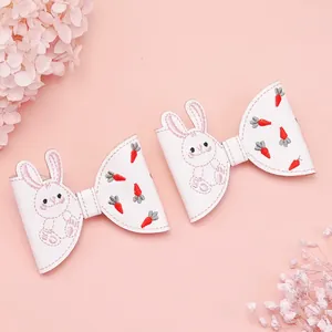 Vue détaillée des barrettes en similicuir blanc avec broderie lapin et carotte.