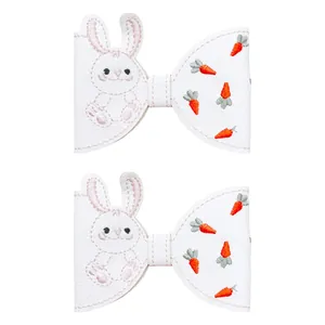 Paire de barrettes à cheveux en similicuir blanc avec lapin et carottes brodés.