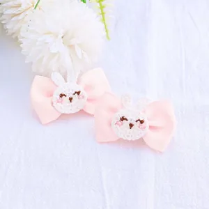 Gros plan détaillé de deux barrettes à ruban rose avec des têtes de lapin de Pâques crochetées.