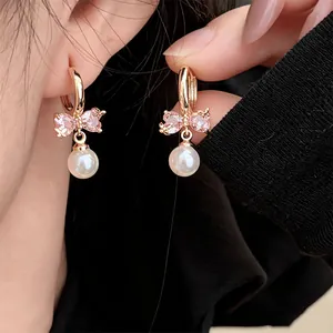 Detailed close-up of vintage style pink zircon butterfly earrings with elegant white pearl dangles